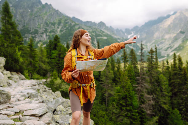 istock Stylish woman looking at map, exploring woods and mountains. 2149404744