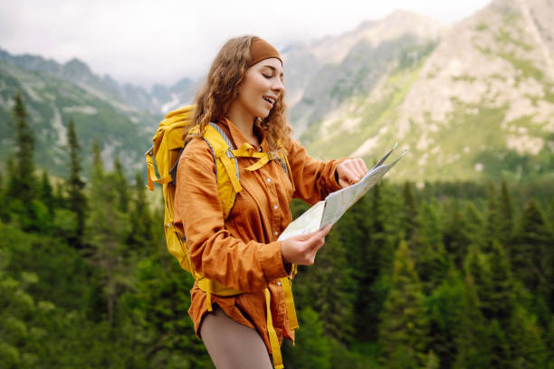 istock Stylish woman looking at map, exploring woods and mountains. 2149404749