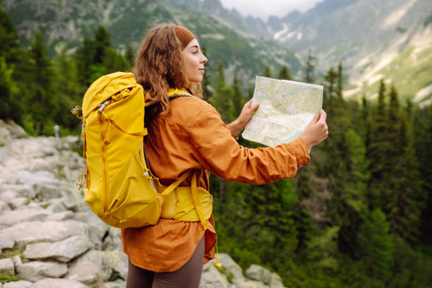 istock Stylish woman looking at map, exploring woods and mountains. 2149404750