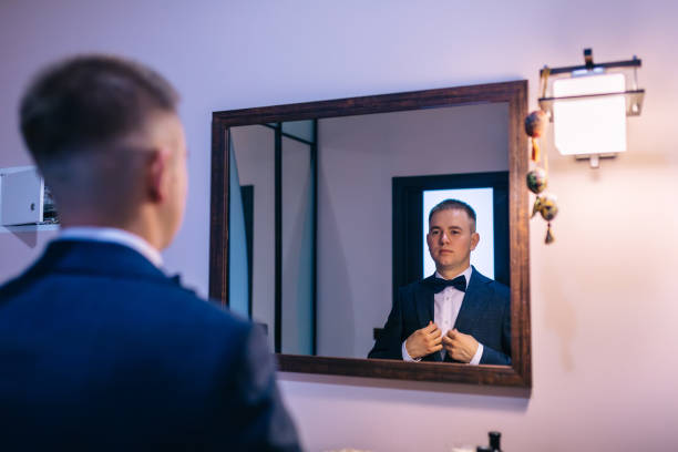 istock a man looks in the mirror and fixes his jacket. 2149405097