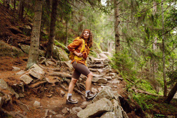 Hiking woman walk with a hiking backpack in spring green forest. Travel, nature, active lifestyle