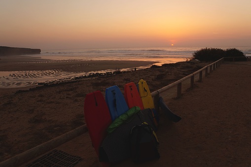 Praia da Bordeira beach with colourful bodyboards at sunset, Algarve, Portugal