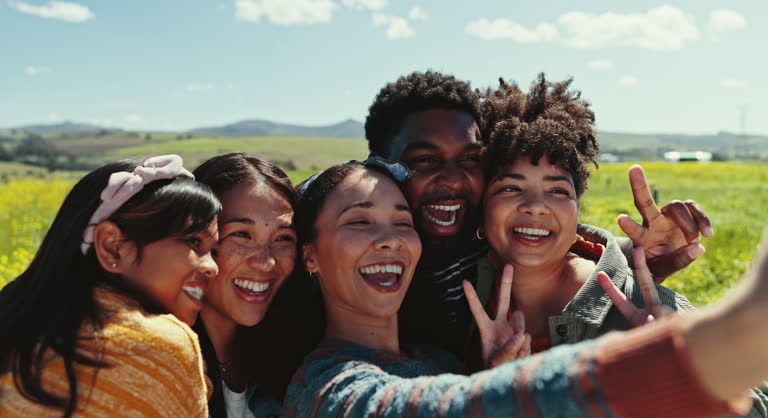 Selfie, friends and peace sign with a group of young people outdoor in nature together for freedom. Emoji, smile or love with men and women posing for a profile picture while in the countryside