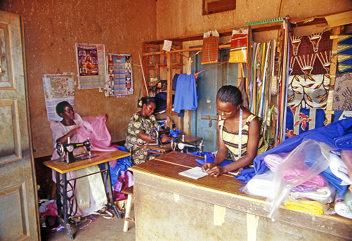 Buikwe region - An unidentified village dressmaker in her shop on July 26, 2004 in village Ajijja, Uganda. Typical colored dresses are the pride of the local women, Africa