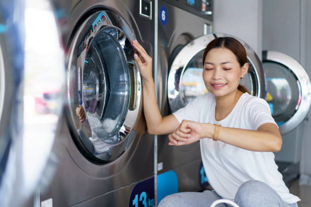 istock Woman washing clothes at self-service laundry KIOSK. 2149409349