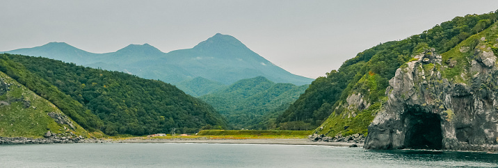 A distant view on a late summer afternoon from a sightseeing cruiser over the famous landmarks of Iwabetsu River terrace and Mt. Rausu in Shiretoko Peninsula, East Hokkaido, Japan.