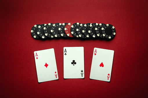 Poker game with a winning combination of three of a kind or set. Playing cards and chips on a red table in a poker club. Winning at a casino depends on luck.