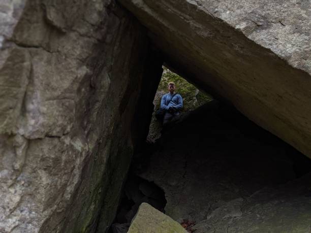 A young man stands on the other side of a cave