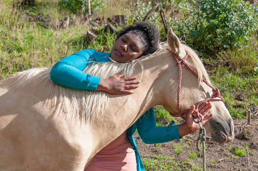 Serene moment of wellness connection between afro woman and horse in lush meadow at sunset