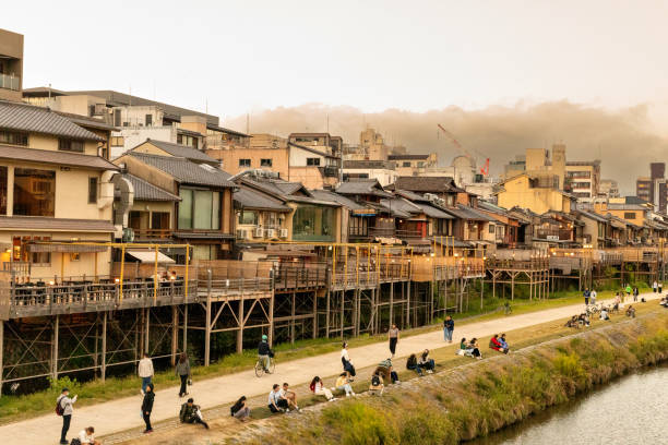 Kyoto, Japan - October 9, 2023: A view across the rooftops and skyline of the city of Kyoto, Japan, with river walking path in view at sunset.