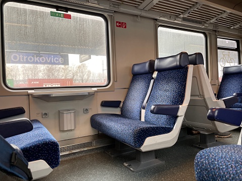 Modern train interior with two rows of blue chairs with the sun coming on the window. German train interior. Eco-friendly public transport.
