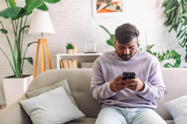 istock Young indian man texting on smartphone at home 2149416594