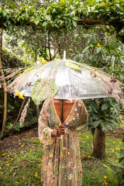 A young black woman in a sheer dress holding an umbrella