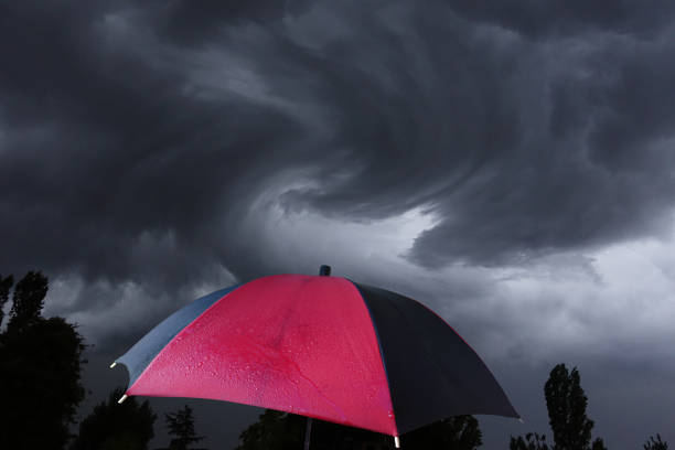 Black umbrella in mid-air against storm cloud with copy space.