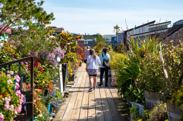 Floating houses in Sausalito during springtime day, with three people walking on boardwalk