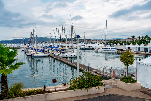 Port in Left part of Croisette (maybe port Pierre Canto)  with sailboats smaller 8 meters length and large catamarans . people in distance  and blurred motion