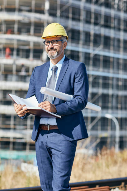 senior businessman architect helmet construction site building architecture tablet computer protective workwear blueprint plan