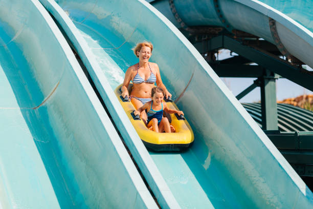 Mother and daughter having fun and enjoys sledging on inflatable ring in a waterpark