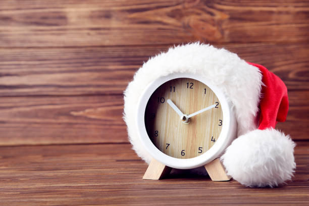 istock Santa hat with round clock on brown wooden background 2149420512