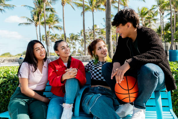 Friends talking sitting on bench at public park