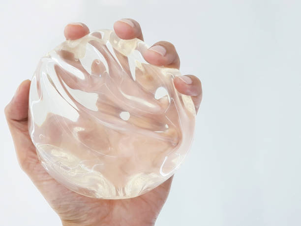 istock Smooth silicone breasts in hands on white background. 2149422665