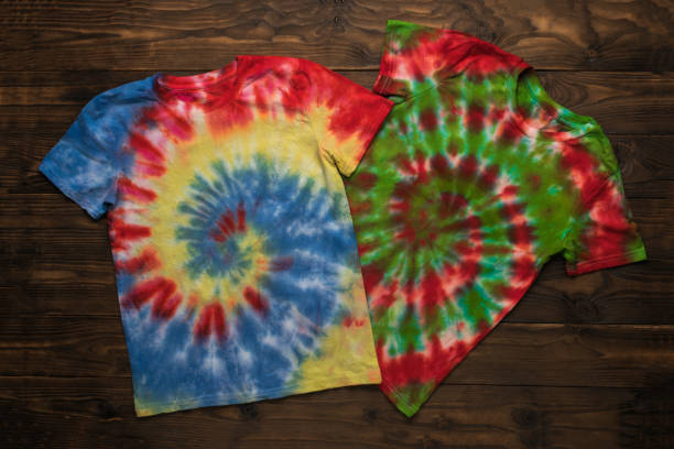 istock Two bright tie dye T-shirts on a dark wooden background. 2149423158