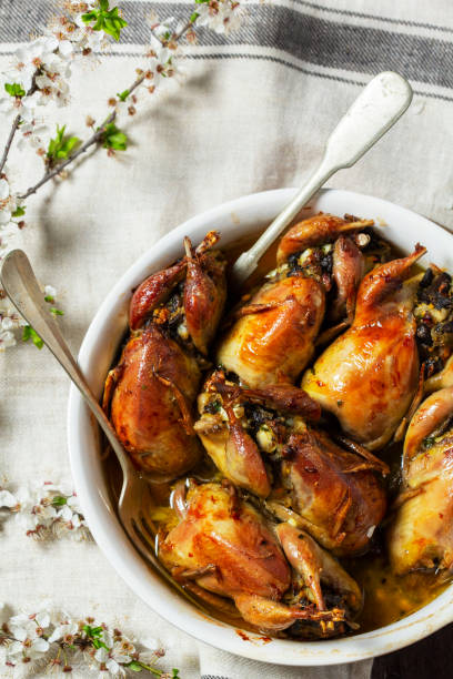 istock Baked quail stuffed with mushrooms, eggs and bread in a ceramic form on a wooden table. 2149424664
