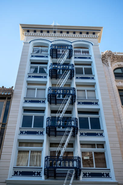 Facade of white building with fire escape stairs in San Francisco during springtime day