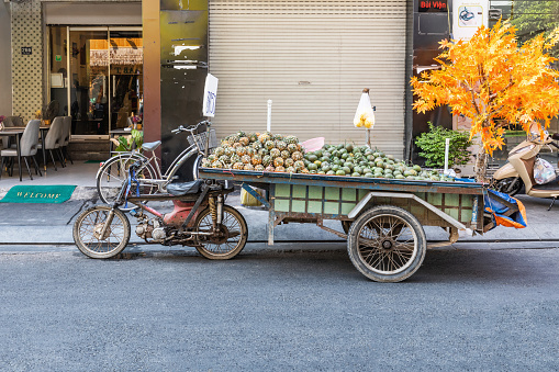 Selling fruit on a motorcycle with a trailer on the street in downtown Ho Chi Minh City, Vietnam