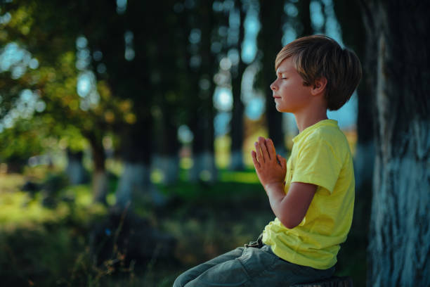 Cute boy meditates in nature with closed eyes