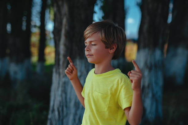 Cute boy meditates in nature with closed eyes