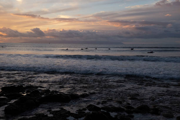 2 surfers on 2 waves at sunset.  Surfers are in 100% silloette; cannot see their faces