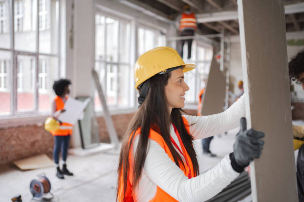 istock Caucasian female construction worker carrying drywall on construction site 2149432122