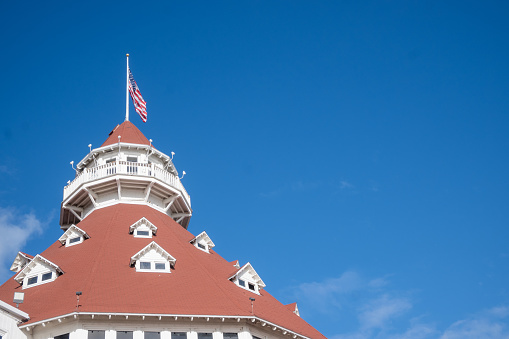 San Diego, CA. Hotel del Coronado roof and American flag, with plenty of blue sky copy space. Built in 1888, this hotel is a historical tourist attraction in the island of Coronado.