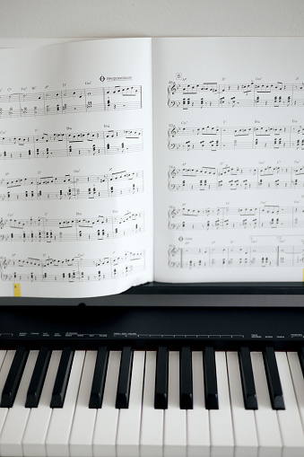 electronic piano keys and music sheets, black and white colors.