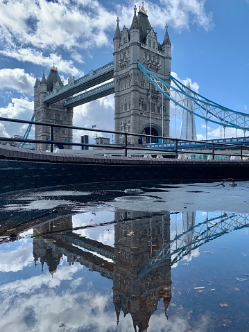 A reflection of tower bridge in a puddle with blue sky