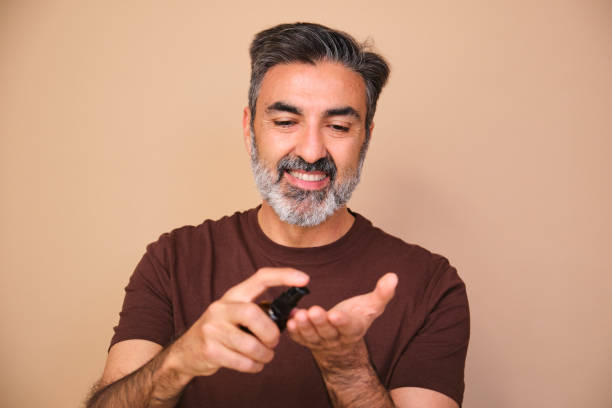 A man is applying lotion to his face. He is smiling and he is happy. Concept of relaxation and self-care.