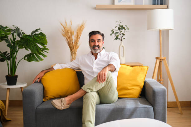 istock A man is sitting on a couch in a living room. 2149434961