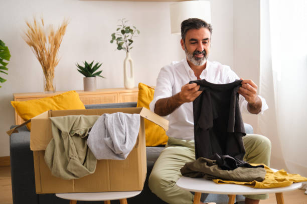 istock A man is sitting on a couch donating clothes for charity. 2149435065