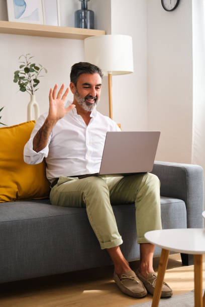 istock A man is making a videocall sitting on a couch with a laptop in front of him. 2149435076