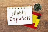 notebook with inscription do you speak spanish on spanish, pen, spain flag, marker on wooden brown desktop 1