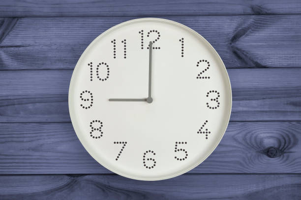 istock Round white wall clock at 9 o'clock on dark gray blue wood background. 2149437816