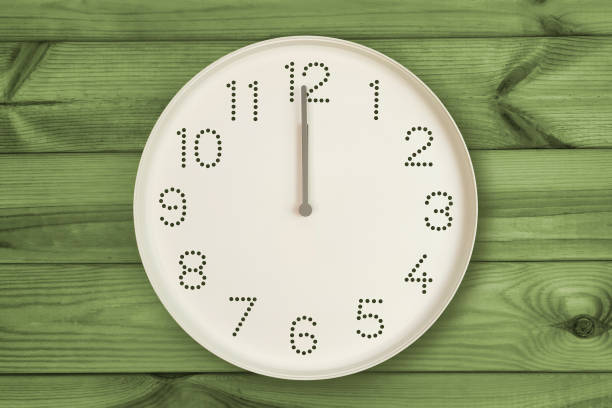 istock Round white wall clock at 12 o'clock on green wood background. 2149437830