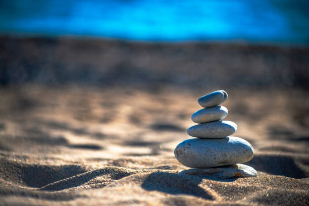 Find harmony amidst the coastal breeze – stones delicately balanced atop each other, a serene spectacle by the sea.