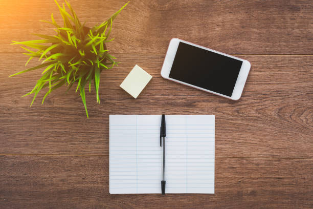 smartphone, notebook and pen on a brown wooden desktop