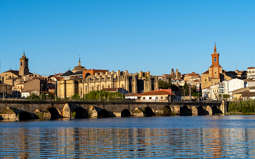 Panoramic view of the town of Alba de Tormes and the river Tormes from the river bank with the stone bridge and the castle duques de Alba. Salamanca, Spain