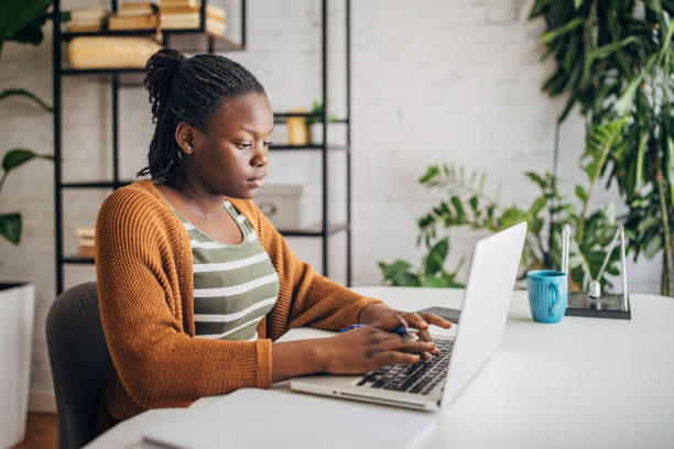 istock Focused young woman working on laptop at home 2149444261