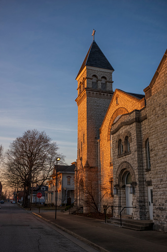 The sunset's glow shines on the bell tower of a Catholic church made of cobblestone, located in the midwest United States of Vincennes, Indiana.
