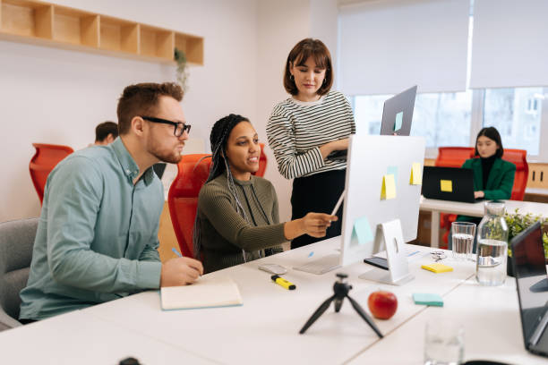 istock Skilled African female mentor or executive manager boss teaching diverse internes, explaining work pointing at computer screen. Team leader supervisor training 2149447274