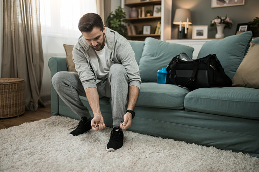 Man tying his shoes at home and getting ready for a workout.